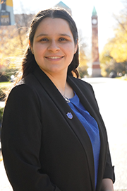 A headshot photo of Andrea Sedano with a clocktower and trees in the background.