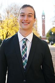 A headshot of Ben Kemper with a clocktower and trees in the background.