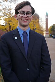 Headshot photo of Chris Brault with a clocktower and trees in the background.