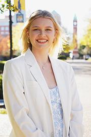 A headshot photo of Mariya Yasinovska with a clocktower and trees in the background.