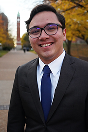 A headshot photo of Nate Reyes with a clocktower and trees in the background.